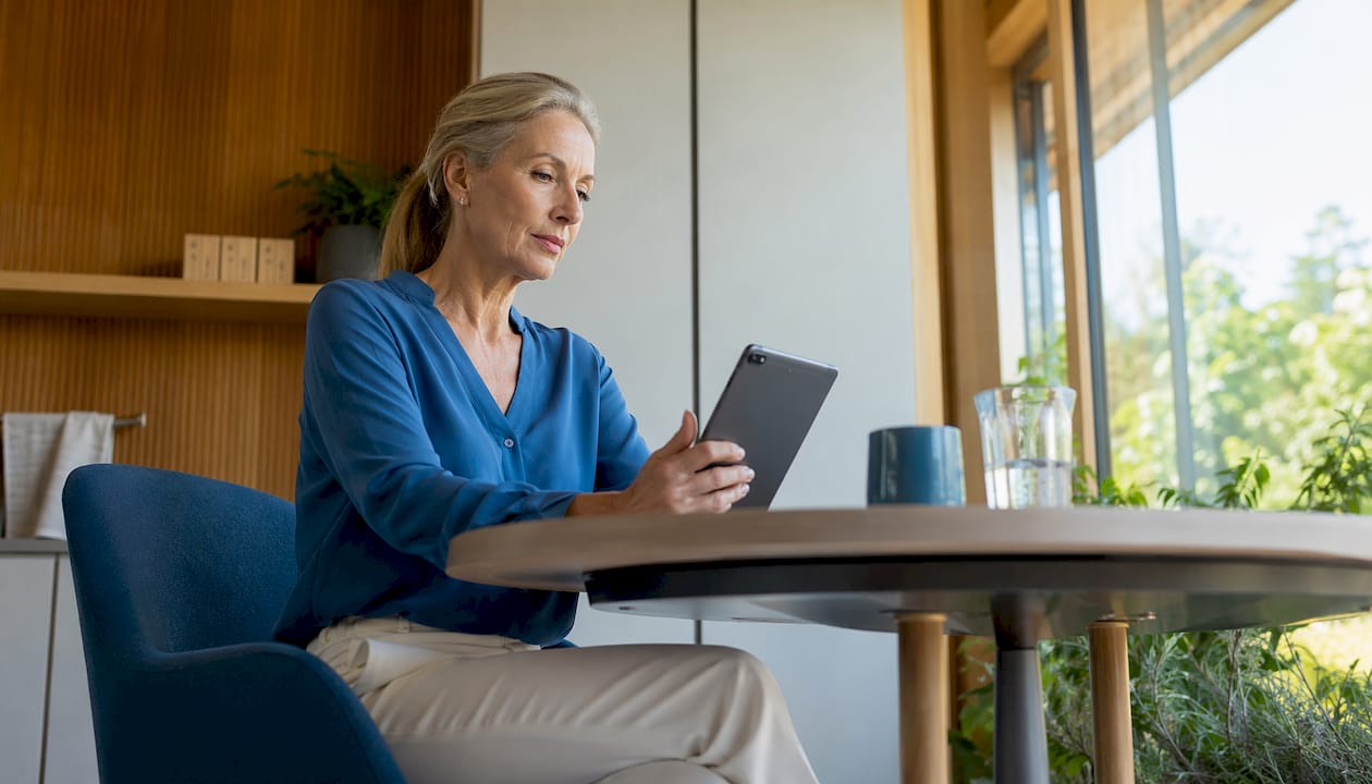 Eine Ärztin ist seitlich zu sehen, wie sie im Praxisbüro mit einem Tablet arbeitet.